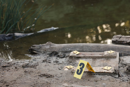 Forensic expertise. Crime scene with evidence and marker near lake outdoors