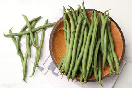 Fresh pea pods, napkin and bowl on white table, flat lay