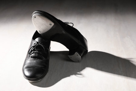 Pair of shoes for tap dance on white wooden floor. Space for text