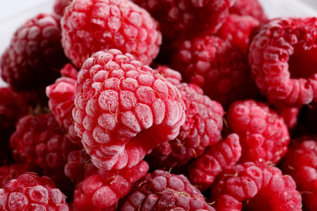 Many ripe frozen raspberries as background, closeup