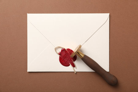 Envelope with wax seal, twine and stamp on brown background, top viewの写真素材