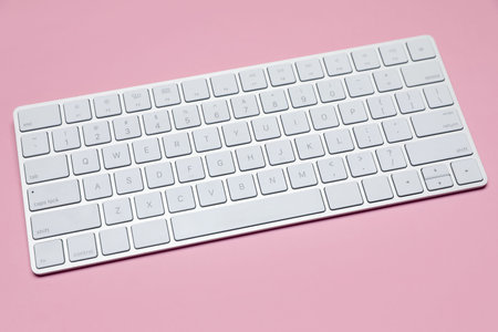 Modern white wireless keyboard on pink background