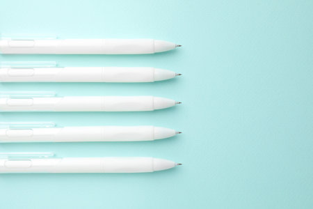 White pens on light blue background, flat lay. Space for text