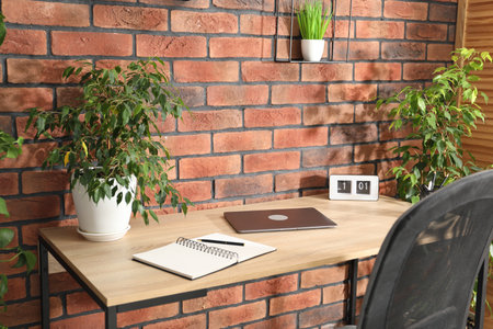 Stylish workplace with laptop, stationery and floral decor in office. Biophilic interior designの写真素材