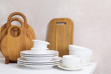 Different clean white dishware and wooden cutting boards on counter