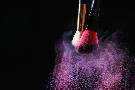 Makeup brushes with colorful eye shadows on black background, closeup. Space for text