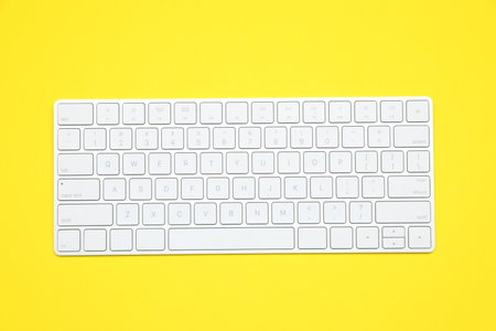 Modern white wireless keyboard on yellow background, top viewの写真素材