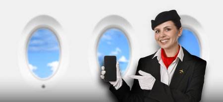 Air hostess pointing at mobile phone near windows in plane