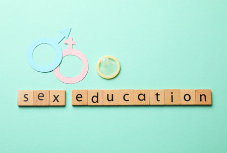 Words Sex Education made of wooden squares, gender symbols and condom on turquoise background, flat layの写真素材