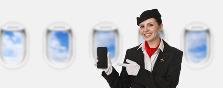 Air hostess pointing at mobile phone near windows in plane