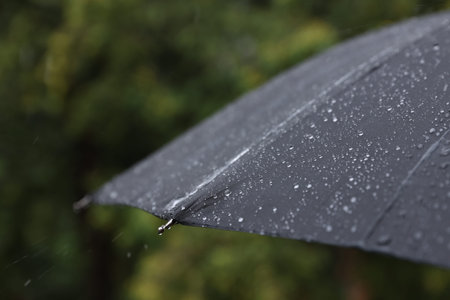 Black umbrella under heavy rain outdoors, closeupの写真素材