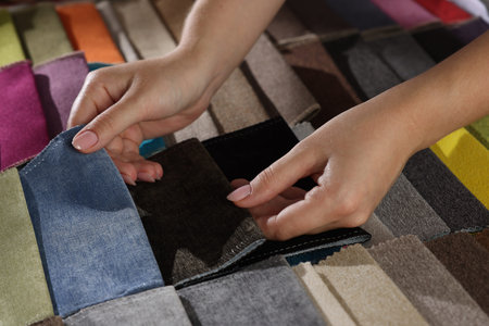 Woman choosing fabric among different samples indoors, closeup