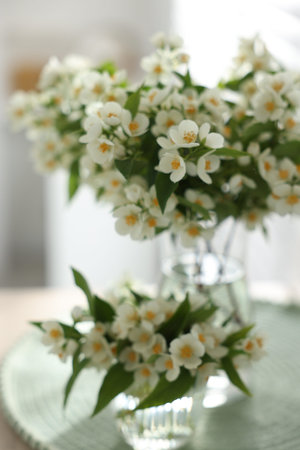Bouquet of beautiful jasmine flowers in vase on table indoors, closeupの写真素材