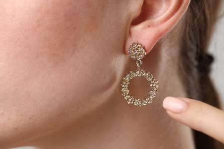 Woman pointing at her stylish earring, closeup
