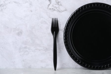 Disposable plastic plate and fork on light gray table, space for textの写真素材