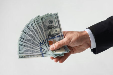 Man with dollar bills on light background, closeupの写真素材