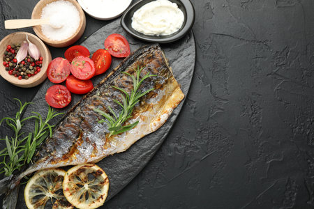 Homemade seafood dish. Tasty roasted mackerel served with spices and sauce on black table, flat lay. Space for textの写真素材
