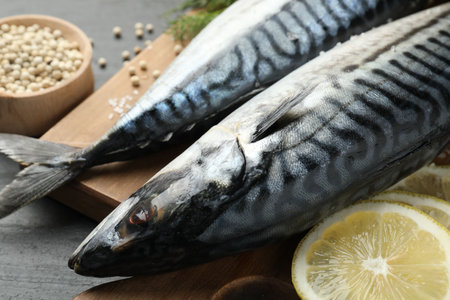Fresh raw mackerels and spices on black table, closeup. Seafood delicacies