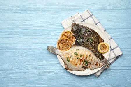 Homemade seafood dish. Tasty roasted flounder fish with herbs and lemon slices on light blue wooden...
