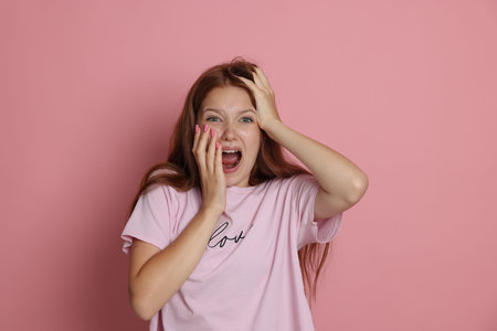 Teenage girl suffering from panic attack on pink backgroundの写真素材