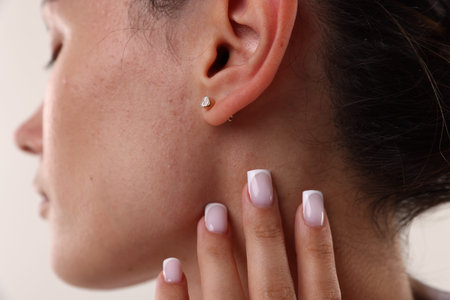 Woman wearing stylish earring on light background, closeup