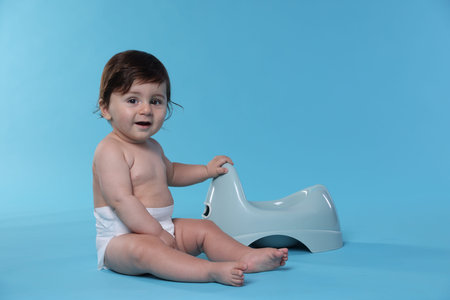 Cute little baby sitting on light blue background