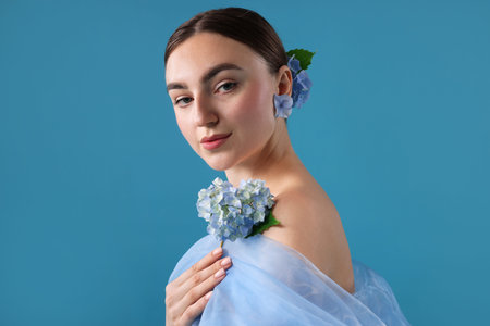 Portrait of beautiful woman with hortensia flowers and cloth on blue backgroundの写真素材