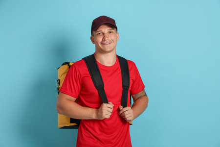 Courier with thermo bag on light blue background. Food delivery service