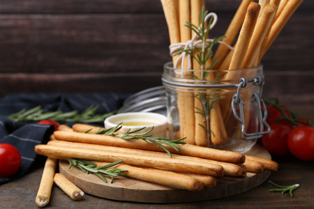 Delicious grissini sticks and rosemary on wooden table, closeup