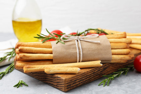 Delicious grissini sticks and rosemary on gray table, closeup