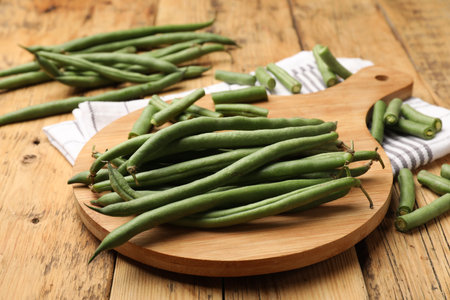 Many raw green beans on wooden table, closeup