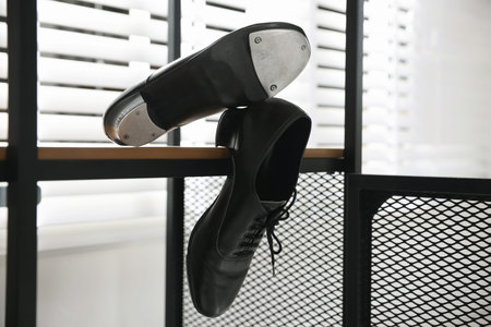 Pair of shoes for tap dance on wooden shelf indoors