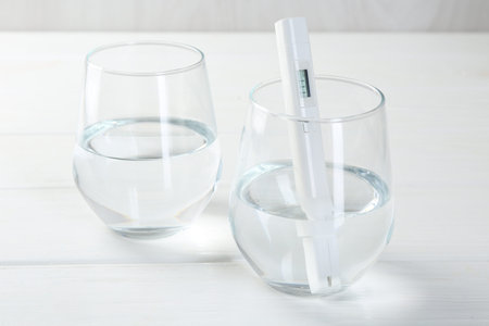 Nitrate tester in glass of water on white wooden table, closeup