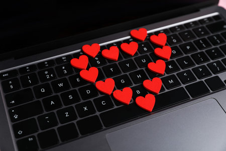 Online dating site. Many red hearts on laptop, closeup