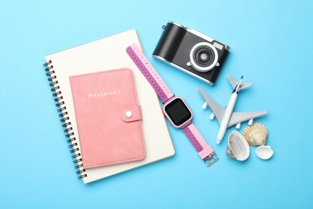 Time for summer vacation. Passport, notebook, toy plane, camera, smart watch and seashells on light...
