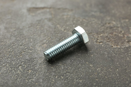 One metal bolt on grey table, closeup