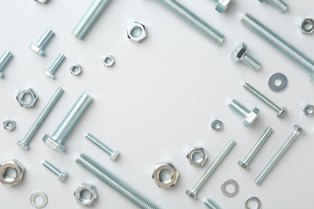 Metal bolts and nuts on white background, flat lay. Space for text