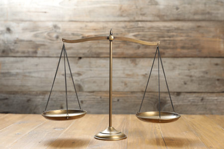 Golden scales of justice on wooden table