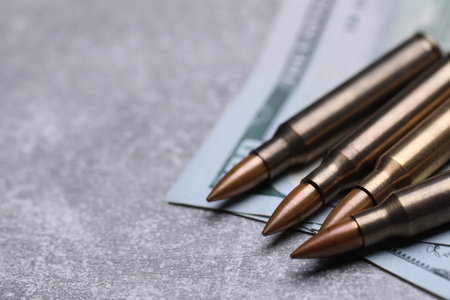 Bullets and dollars on grey table, closeup. Space for text