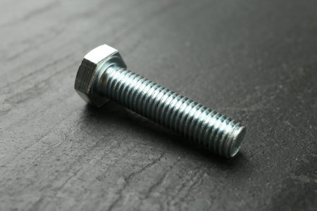 One metal bolt on black table, closeup