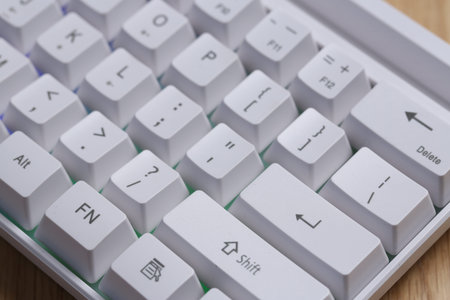 Modern white keyboard with RGB lighting on wooden table, closeup