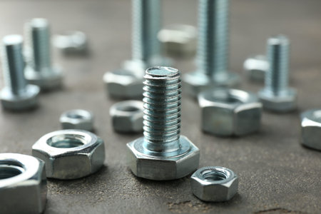 Metal bolts and nuts on grey table, closeup