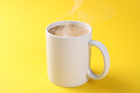Aromatic coffee in cup on yellow background, closeup. Mockup for designの写真素材