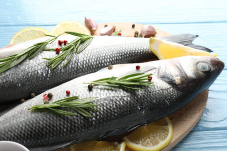 Fresh raw seabass with spices on blue wooden table, closeup. Fish and seafood delicacies