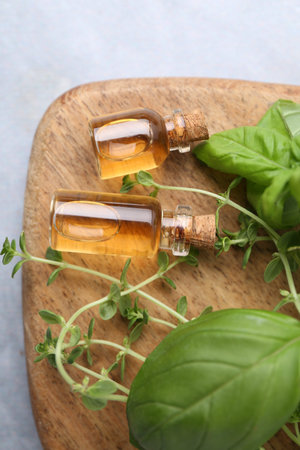 Bottles of essential oil and herbs on wooden table, top viewの写真素材