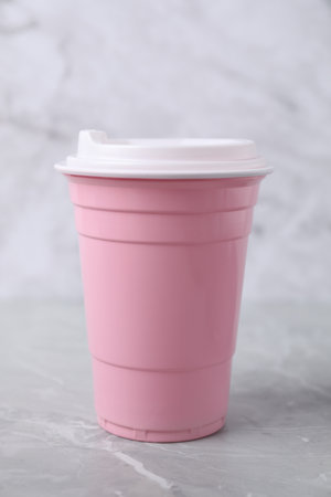 Pink disposable plastic cup on light grey tableの写真素材