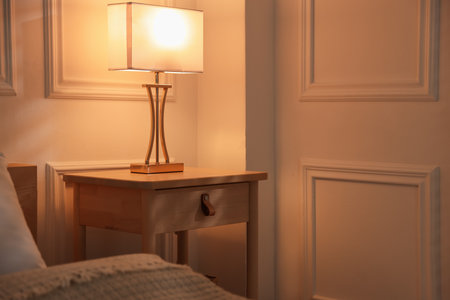 Bedside table with lamp near bed indoorsの写真素材