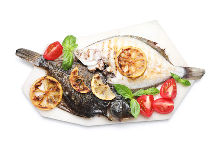 Tasty roasted flounder fish with tomatoes, basil and lemon slices isolated on white, top view. Homemade seafood dishの写真素材