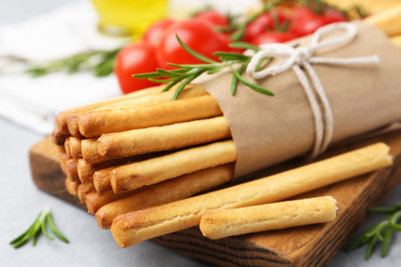 Delicious grissini sticks and rosemary on grey table, closeup