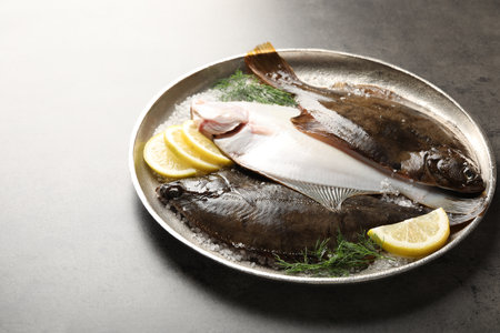 Fresh flounder fish, salt, lemon and dill on grey textured table, closeup. Raw seafoodの写真素材